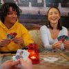 Drei Personen sitzen am Tisch und spielen mit den Spielköpfe-Karten