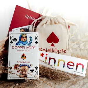 Das Spielköpfe Doppelkopfdeck mit einer Postkarte, einem Baumwollbeutel und einem *innen-Sticker 
